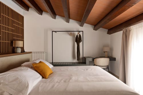 Modern bedroom at Dimora Silva Nature Suites with wooden beamed ceiling, white bedding, mustard pillow, and minimalist