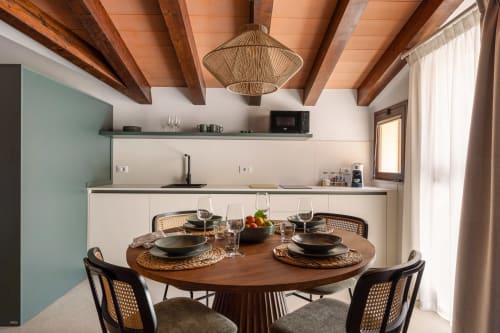 Modern kitchen-dining area at Dimora Silva Nature Suites with wooden ceiling beams, round table, and contemporary design in