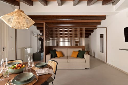 Dimora Silva suite with beamed ceiling, modern beige sofa, dining area, woven pendant light, and wooden details