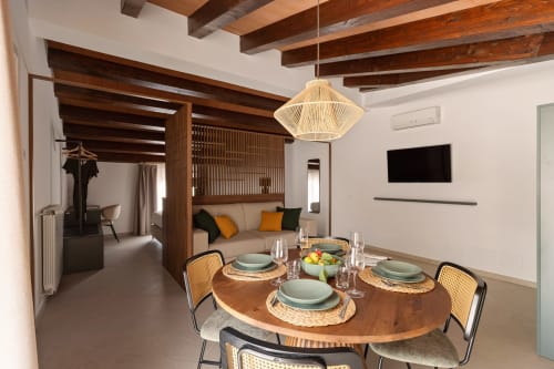 Modern dining area at Dimora Silva 5 with round wooden table, rattan chairs, and rustic wooden beams at Dimora Silva Nature