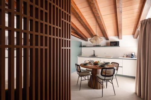 Modern kitchen and dining area at Dimora Silva Nature Suites with wooden beams, round table, and contemporary design