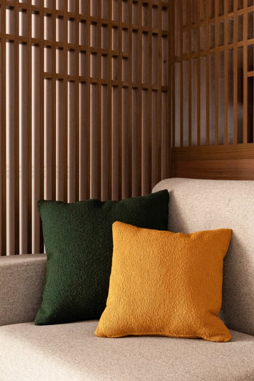 Cozy bedroom corner at Dimora Silva Nature Suites with beige sofa, green and golden pillows, wooden slatted headboard