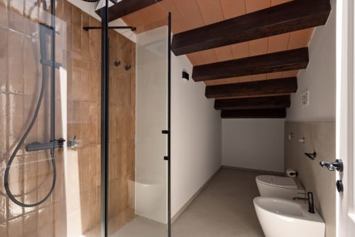 Modern bathroom at Dimora Silva Nature Suites with shower, double sinks, and exposed wooden beams