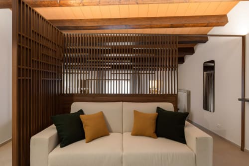 Appartamento moderno a Dimora Silva con divano color crema, baldacchino in legno, cuscini arancioni e neri, travi a vista