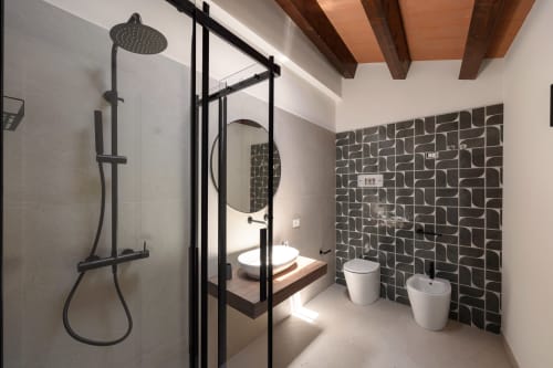 Bagno moderno nell'appartamento Dimora Silva 6 con parete piastrellata geometrica nera, doccia a pioggia e finiture contemporanee