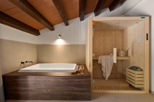 Lussuoso bagno della Dimora Silva Nature Suites con sauna in legno, vasca incassata e soffitto con travi a vista