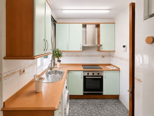 Cocina moderna del hotel Holibai en Baiona con muebles menta, encimeras de madera y electrodomésticos de acero inoxidable