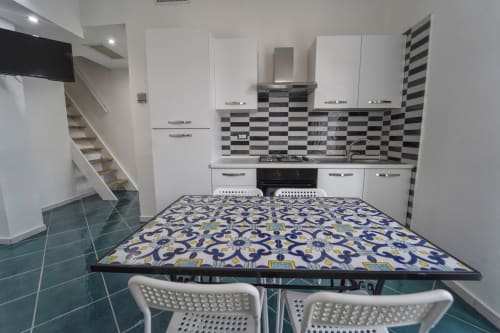 Moderna zona cucina-soggiorno all'Antico Palazzo del Corso con mobili bianchi, rivestimento a scacchiera e tavolo da pranzo a Ponente