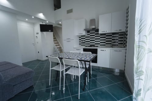 Cucina e zona dining moderna con armadietti bianchi, rivestimento bianco e nero, tavolo da pranzo all'Antico Palazzo del Corso,