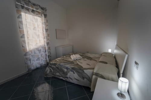Camera moderna nell'Antico Palazzo del Corso con letto, finestra con tende decorate, pavimento in scuro e arredamento contemporaneo