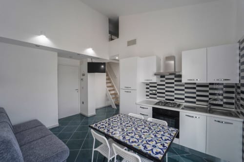 Cucina-sala da pranzo moderna all'Antico Palazzo del Corso con mobili bianchi, rivestimento a scacchiera e tavolo decorato