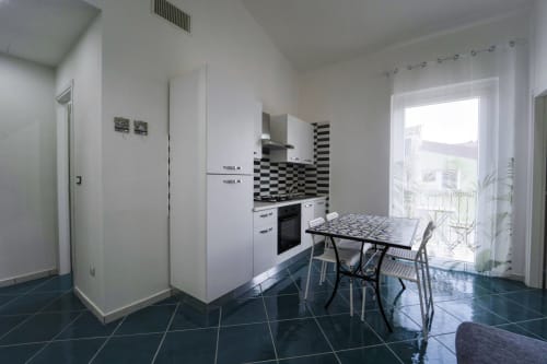 Cucina e zona pranzo moderna dell'appartamento Ponente ad Antico Palazzo del Corso, Mirto Crosia con mobili bianchi,