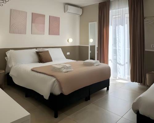 Camera moderna presso Maison ì Room con letto queen size, biancheria beige, arte contemporanea alle pareti e accesso alla terrazza a Reggio di