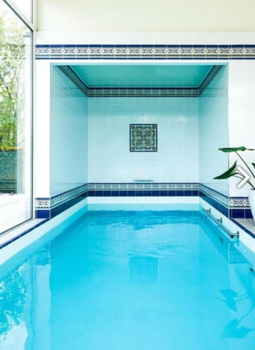 Luxe binnenzwembad in Villa Bianca met turquoise tegels, decoratieve randen en natuurlijk licht van ramen