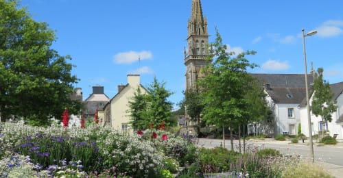 Hôtel De La Vallée à Saint-Gilles-Vieux-Marché avec jardins fleuris colorés, bâtiments en pierre traditionnels et clocher
