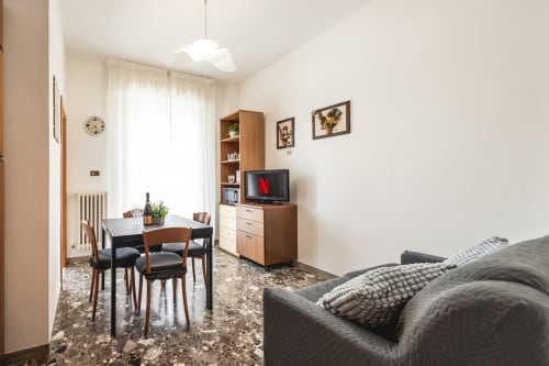 Moderno salotto con zona pranzo, TV, mobili in legno e vista sulla città a Rimini presso AmazHome