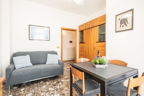 Zona living dell'appartamento AmazHome a Rimini con divano grigio, tavolo da pranzo, mobili in legno e vista sulla città