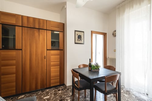 Moderna sala da pranzo dell'hotel AmazHome a Rimini con tavolo nero, sedie in legno e grande armadio in legno