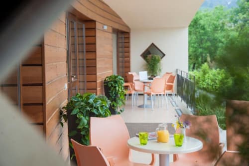 Moderna terrazza lounge dell'Hotel Ristorante alle Querce a Castelbuono con piante verdi, sedie arancioni e bevande