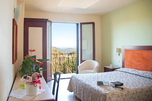 Spaziosa camera d'albergo a Hotel Ristorante alle Querce a Castelbuono con balcone, fiori e vista sul paesaggio montano