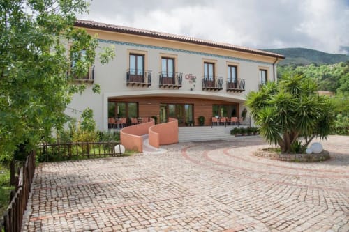 Cortile dell'Hotel Ristorante alle Querce a Castelbuono con pavimenti in terracotta, installazioni di arte moderna e atmosfera mediterranea