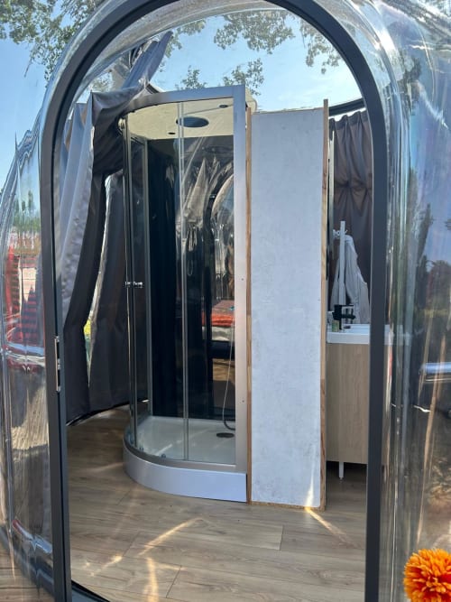 Vue intérieure de la suite bulle Topaze au Bubble Jade avec parois en verre courbe, douche moderne et finitions en bois