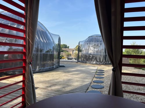 Vue depuis la bulle Topaze de l'hôtel Bubble Jade sur la terrasse du jardin avec terrasse en bois et bulle transparente