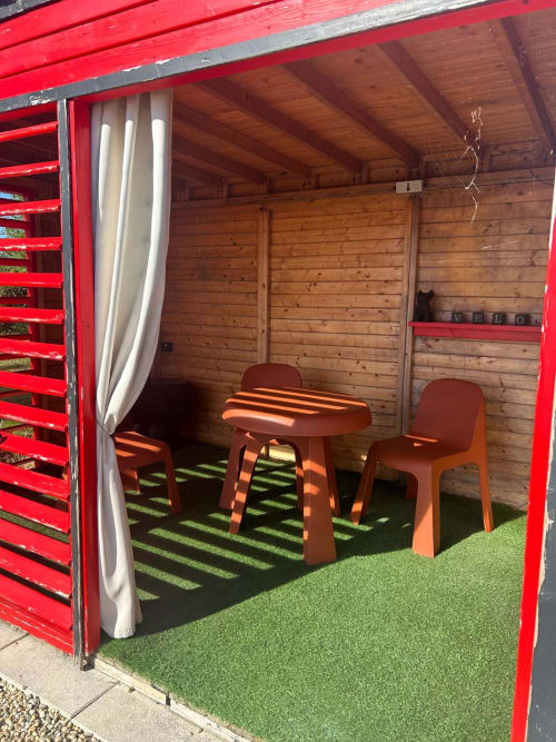 Chambre Bulle Topaze de l'hôtel Bubble Jade avec façade rouge, intérieur boisé, espace détente extérieur, gazon synthétique et privé