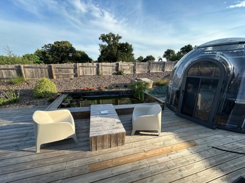 Chambre bulle Émeraude chez Bubble Jade avec terrasse en bois, chaises blanches, table, bassin et jacuzzi privatif en jardin