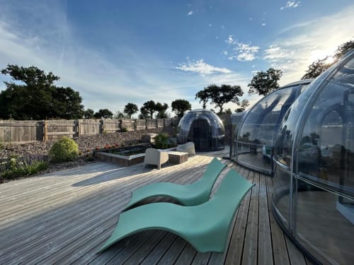 Transats turquoise sur terrasse en bois face aux bulles de glamping de l'hôtel Bubble Jade à Bazouges la Pérouse, France, avec