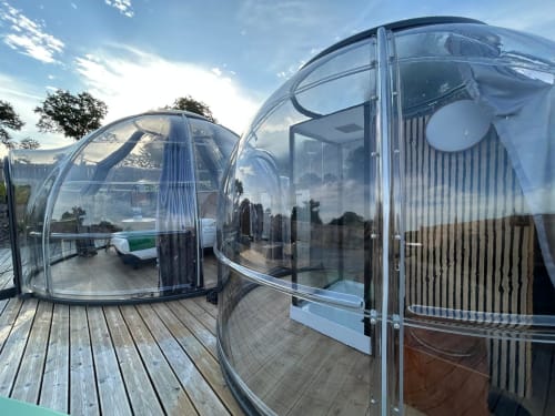 Deux dômes de glamping en bulle transparente avec jacuzzis privés sur terrasse en bois à l'hôtel Bubble Jade de Bazouges la Pérouse