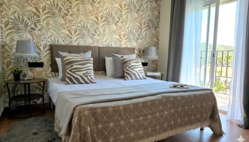 Elegante dormitorio con vistas al mar en Marbella Views, con cojines de cebra, papel pintado botánico y acceso a terraza en Ojén