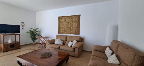 Amplia sala de estar en Villa 3 de Villas del Mar con sofás marrones, TV de pantalla plana, mesa de café de madera y vistas a las montañas