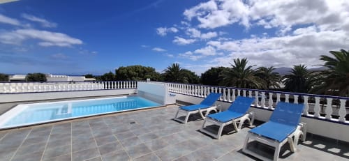 Terraza con piscina en la azotea de Villas del Mar, con tumbonas, vistas a las montañas y palmeras en Puerto Calero