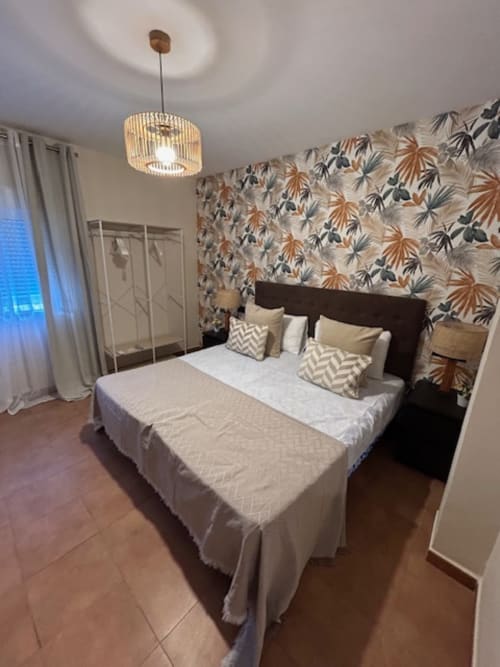 Dormitorio doble moderno en Marbella Views con papel pintado floral, cabecero oscuro e iluminación colgante