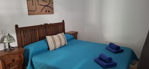 Habitación de Villas del Mar Viña y Cabrera, Puerto Calero con cama de madera, ropa de cama azul y decoración con vista a las montañas