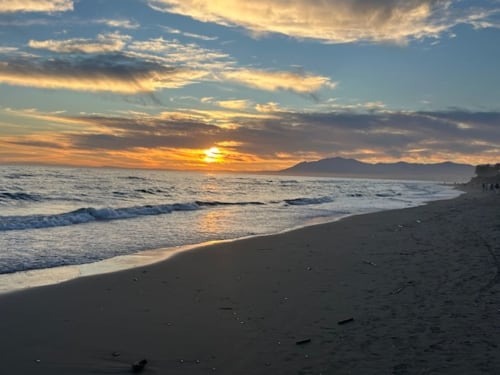 Vista de playa al atardecer cerca de Marbella con olas y montañas, Ojén España