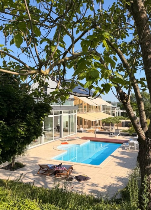 Villa Bianca pool and patio in Dalhem, Belgium with guests relaxing by the blue pool under summer trees