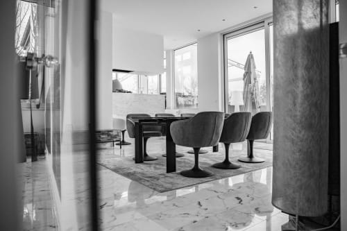 Modern minimalist dining area at Villa Bianca with black table, gray chairs, marble floors, and large windows overlooking