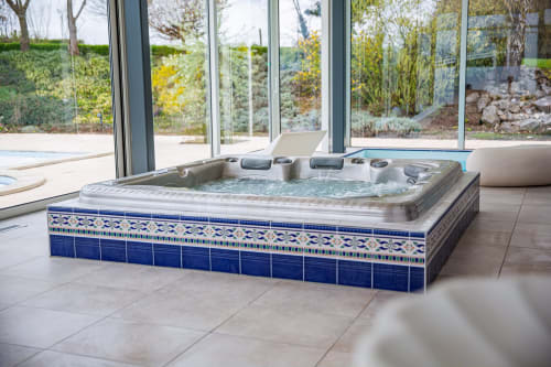 Luxueus bubbelbad met blauwe tegels bij Villa Bianca spa, uitzicht op tuin en landschap in Mortroux Dalhem
