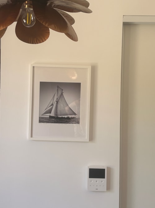 Framed black and white sailboat photograph on cream wall at Maisons Valmer Le Havre, with vintage lamp above and thermostat