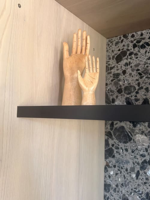 Wooden hand sculptures displayed on black shelf in An heol penthouse at Maisons Valmer, Le Havre