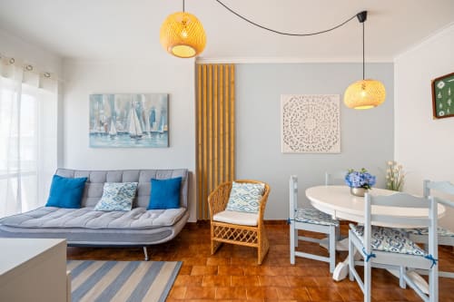 Apartamento Pêra Breeze em Armação de Pêra com sofá cinzento, mesa de jantar, luminárias amarelas e decoração costeira