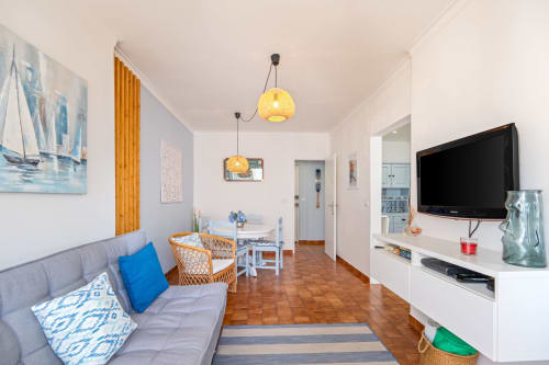 Apartamento Pêra Breeze em Armação de Pêra com sofá cinzento, área de refeições, TV e luminárias pendentes amarelas