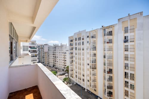 Vista da varanda de edifícios residenciais em Armação de Pêra com horizonte da cidade e céu azul claro
