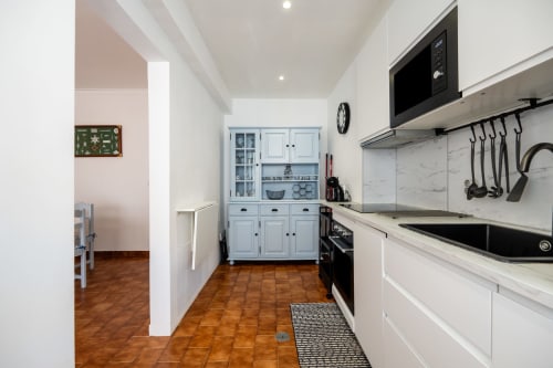 Cozinha moderna do apartamento Pêra Breeze no Happy Nest AL, Armação de Pêra, com armários brancos, backsplash em mármore e