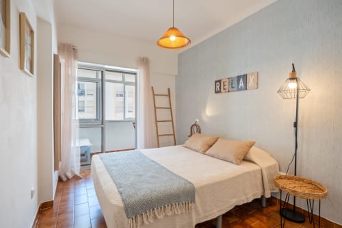 Quarto luminoso na Happy Nest AL com cama queen, luminárias pendentes, vista para a cidade da varanda e móveis modernos em Armação de