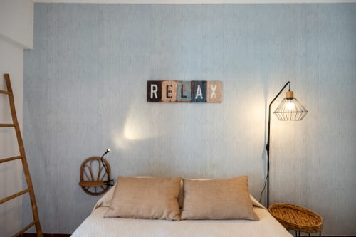 Quarto acolhedor na Happy Nest AL com placa 'RELAX', almofadas bege, luminária de piso e escada de madeira em Armação de Pêra