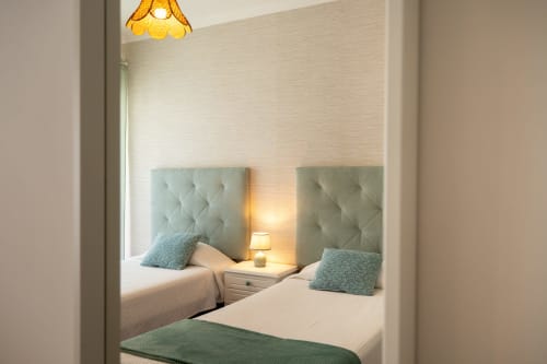 Quarto com duas camas na Pêra Breeze, Happy Nest AL: cabeceiras acolchoadas, luminária de cabeceira e vista para Armação de Pêra