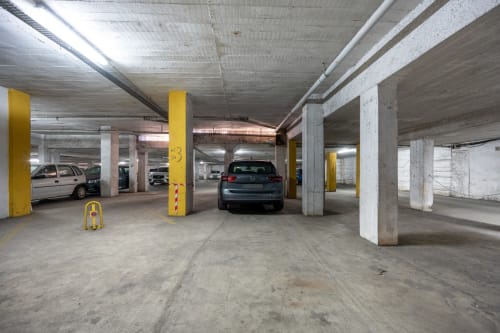 Garagem de estacionamento subterrânea do Happy Nest AL em Armação de Pêra com colunas amarelas e veículos estacionados